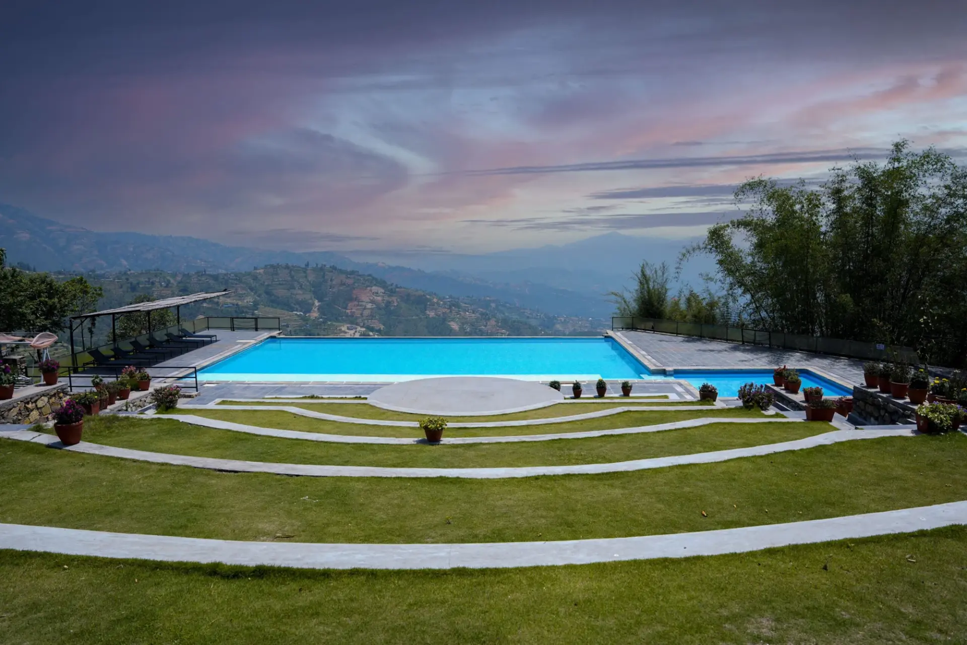 Infinity pool and terraced lawn at Hotel Himalayan Horizon in Dhulikhel, with hills in the background.