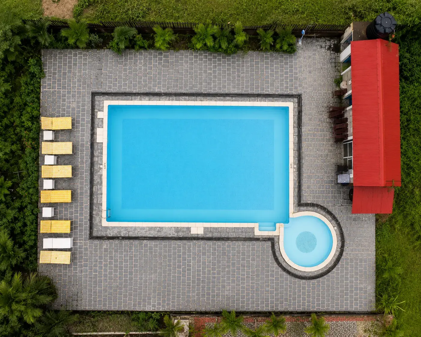 Aerial view of the rectangular swimming pool and adjoining round children’s pool at Center Park Resort, with a paved deck and sun loungers.